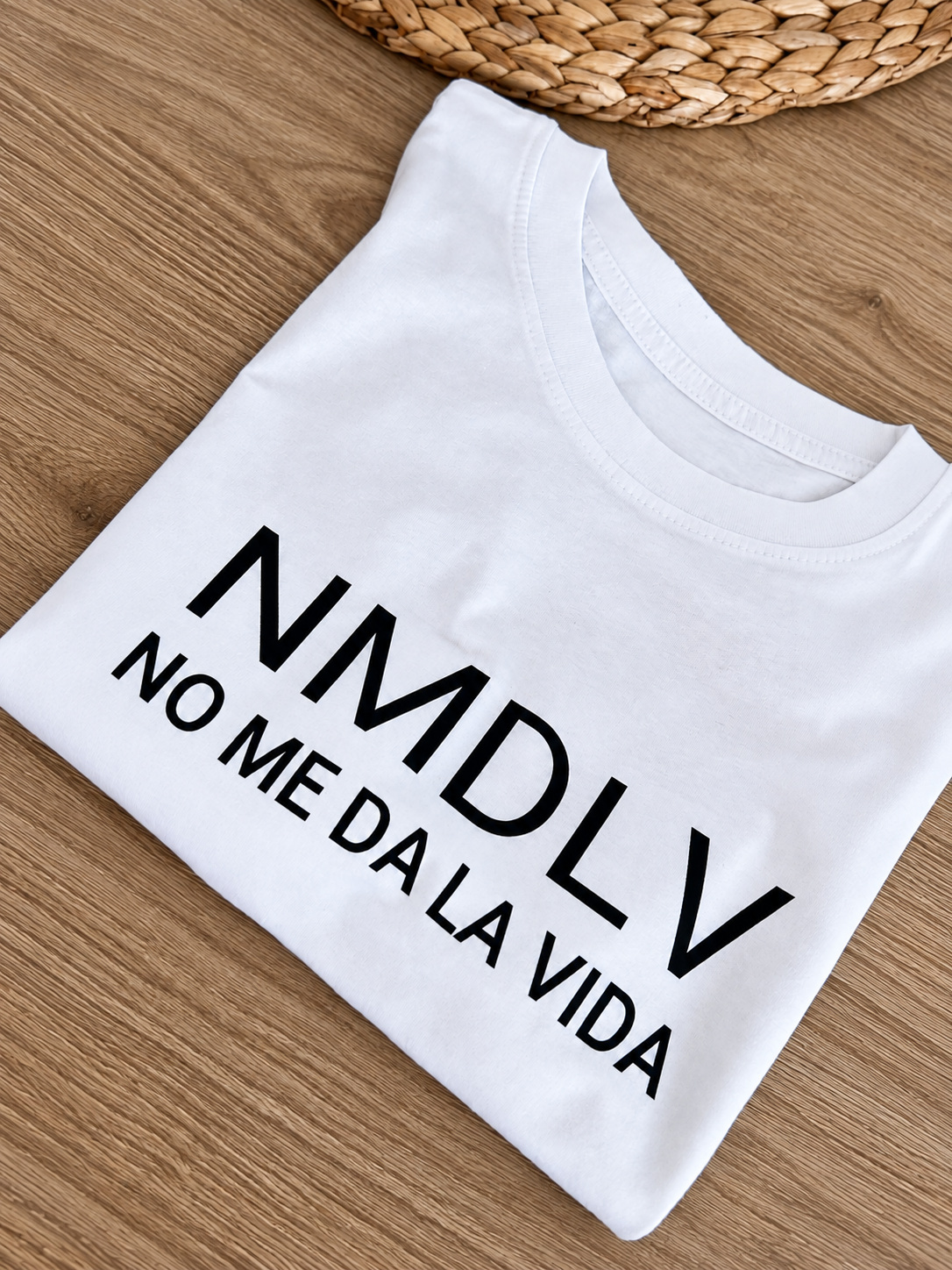 Detalle de camiseta blanca con las siglas NMDLV y la frase No me da la vida.