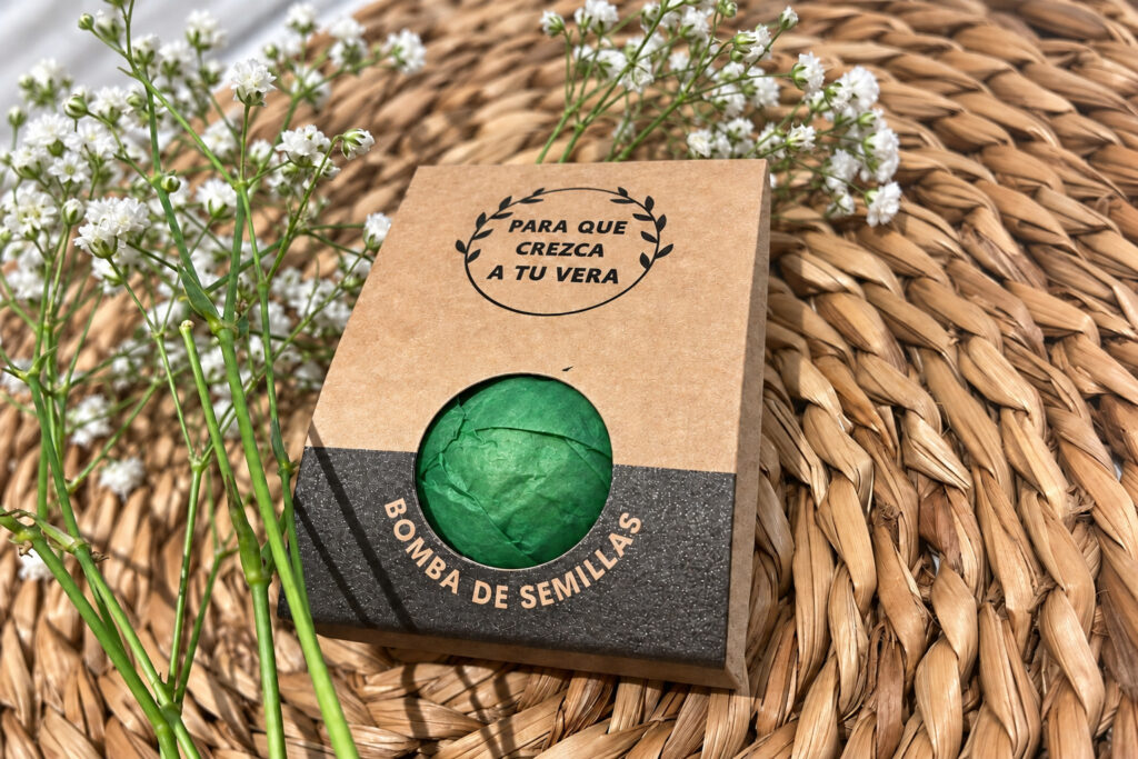 Envase kraft con la frase Para que crezca a tu vera y ventana circular con envoltura verde.