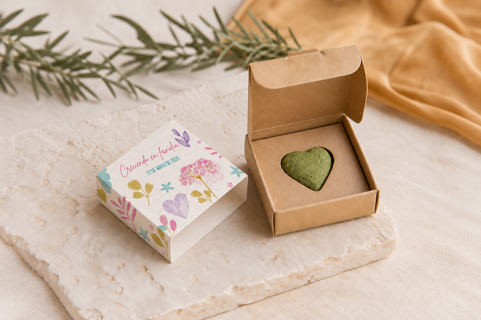 Corazón verde dentro de una caja kraft abierta, junto a una faja con el diseño floral Creciendo en familia.