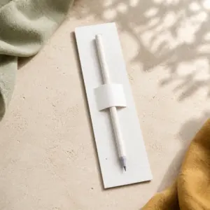 Lápiz blanco de papel reciclado sujeto al centro de un marcapáginas de papel plantable.