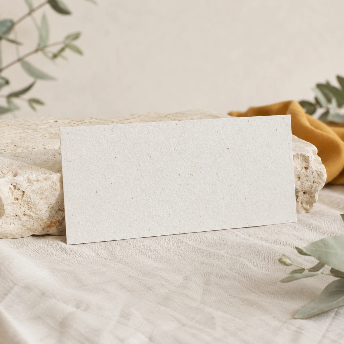 Tarjetón alargado de papel plantable sobre piedra clara y lino