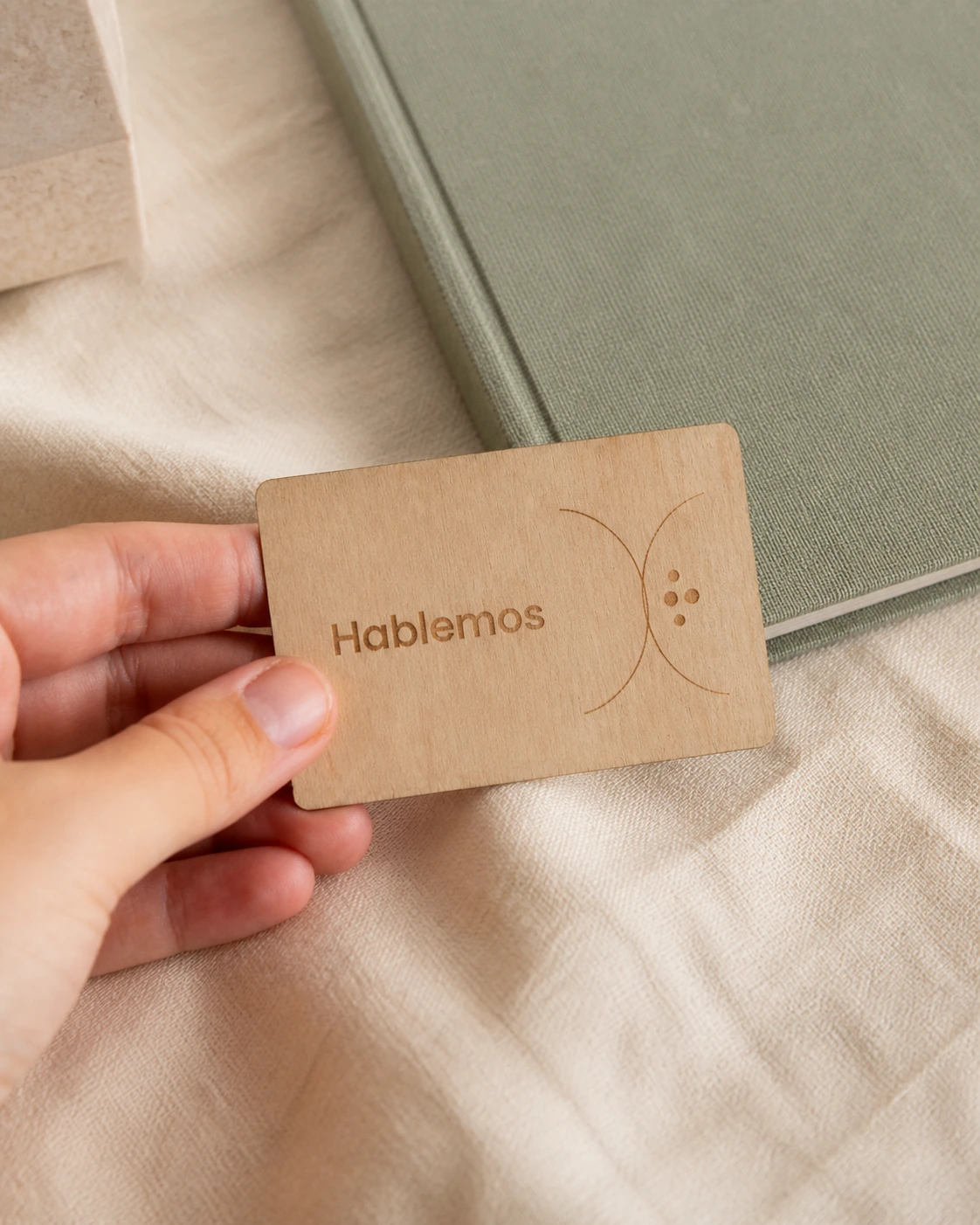 Tarjeta de visita de madera con grabado Hablemos y arcos minimalistas.