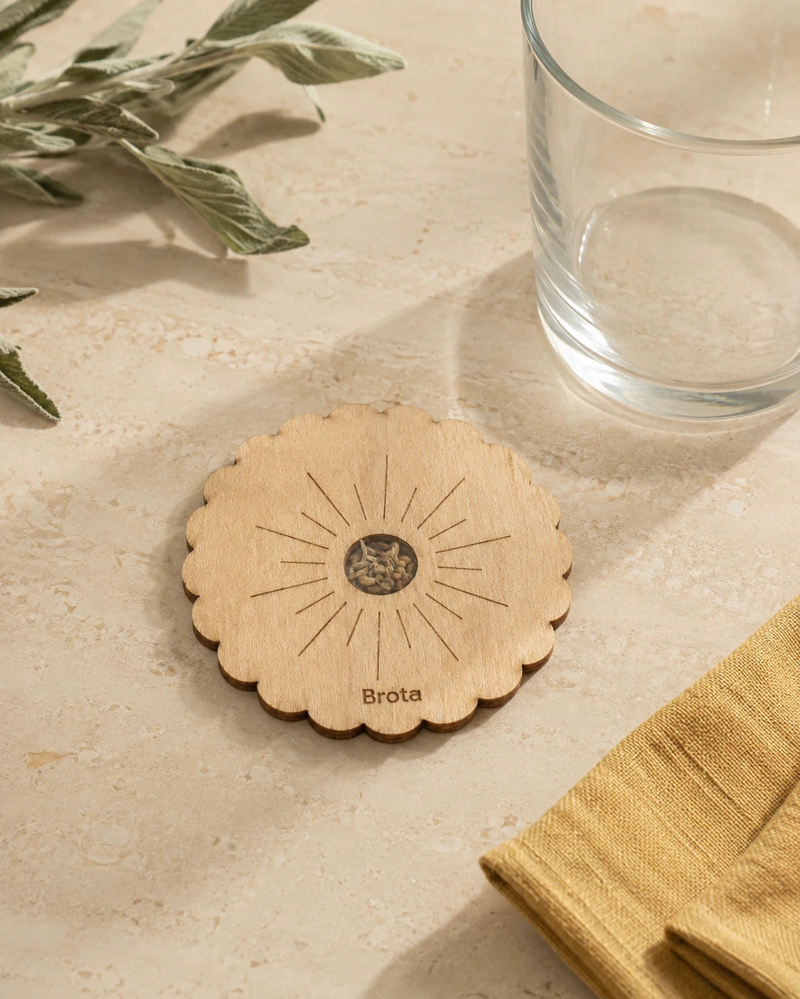 Posavasos de madera con grabado de rayos y palabra Brota junto a un vaso.