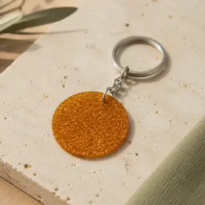 Llavero circular de biomaterial ámbar con cadena y anilla metálicas.