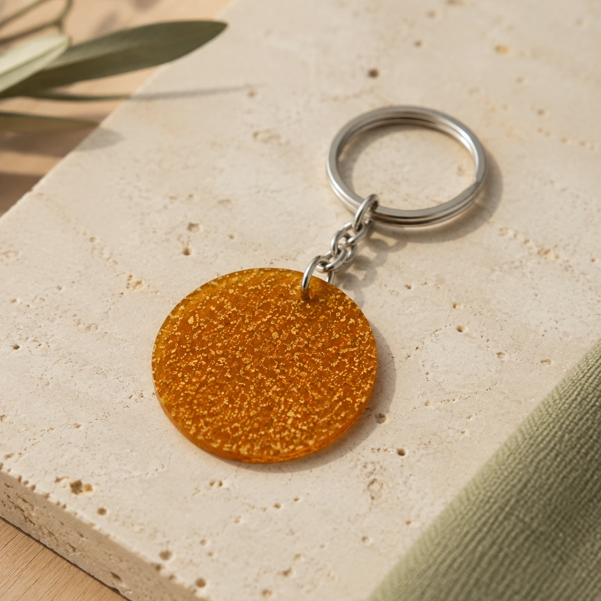 Llavero circular de biomaterial ámbar con cadena y anilla metálicas.