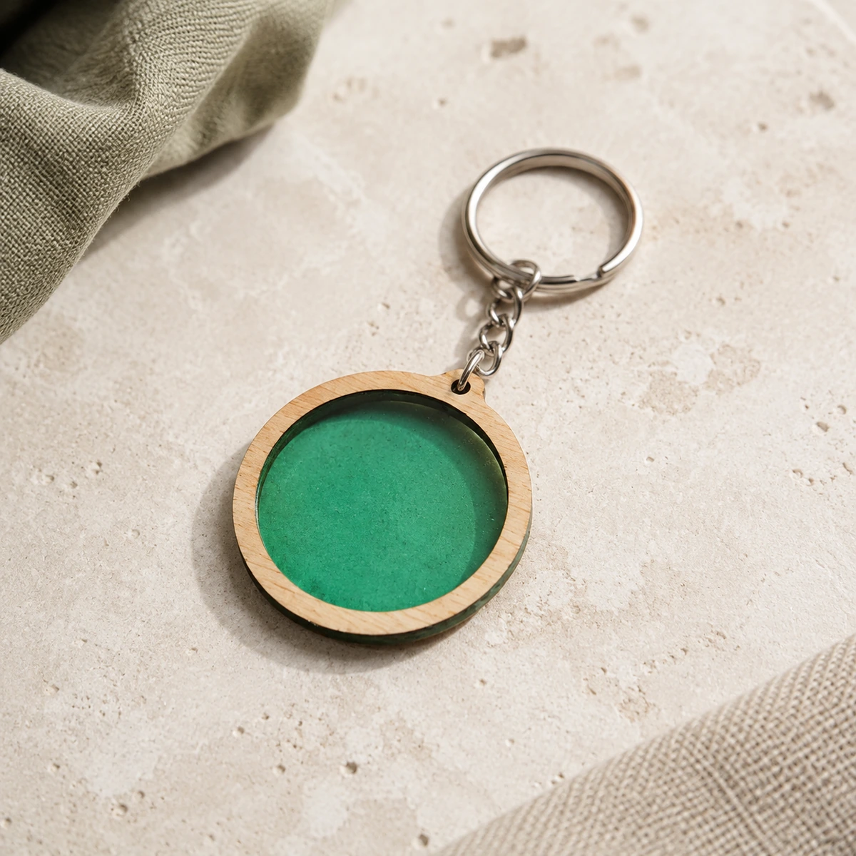 Llavero circular con inserto verde de biomaterial y marco de madera.
