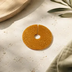 Marcacopas de biomaterial ámbar con orificio central y corte radial.