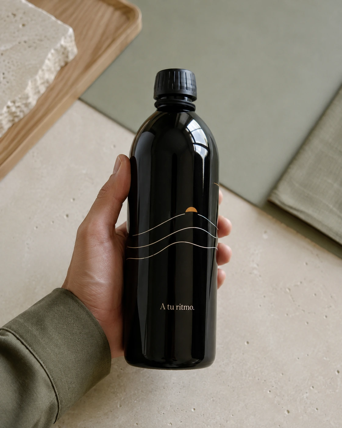 Botella de vidrio oscuro con diseño de líneas y mensaje A tu ritmo.