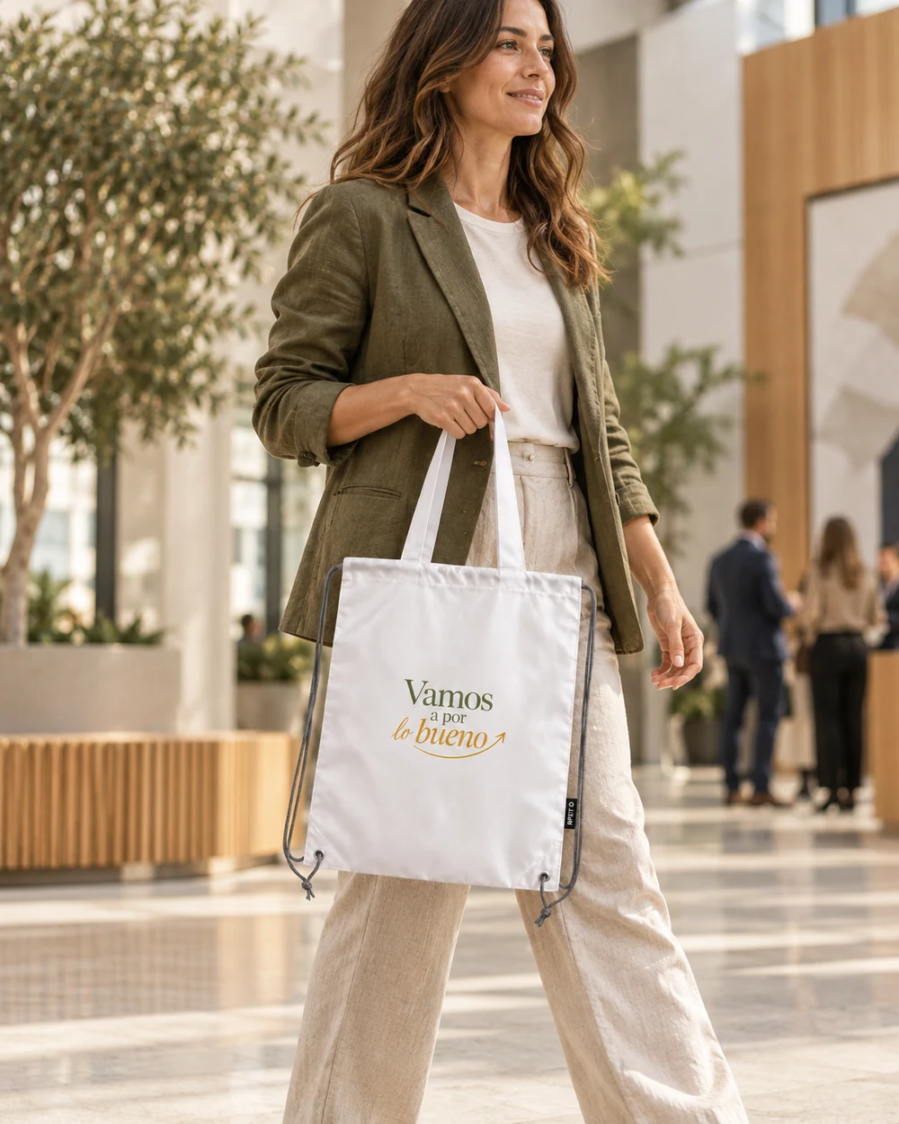 Bolsa Impulso blanca llevada de las asas, con el diseño «Vamos a por lo bueno» a color.